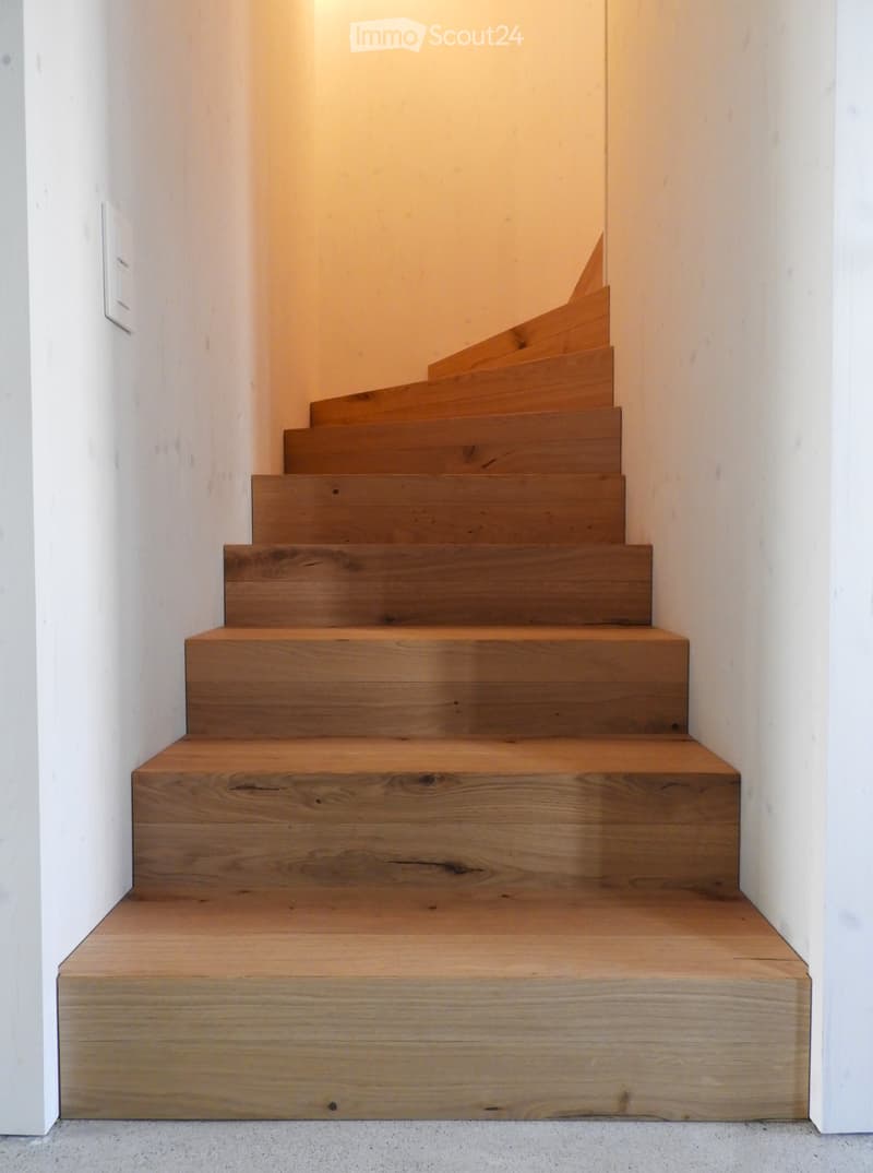 Wooden staircase with warm lighting, white walls, and a modern design.