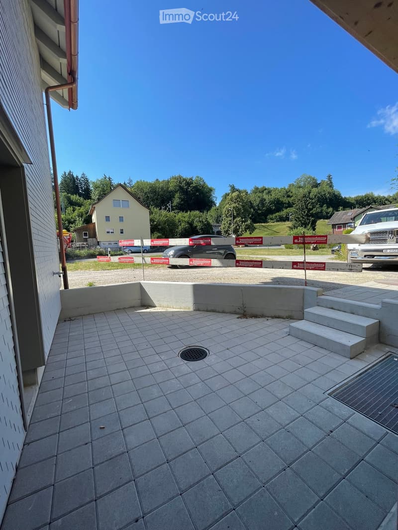 Balcony with tiled floor, low concrete wall, steps leading up, and a drain cover.
