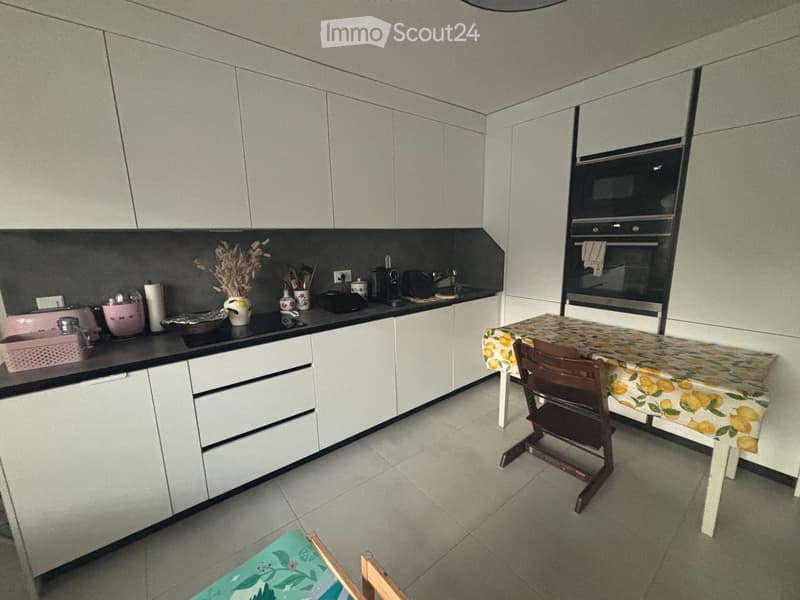 Modern kitchen with white cabinets, black countertops, and a small dining area with a table and chairs.