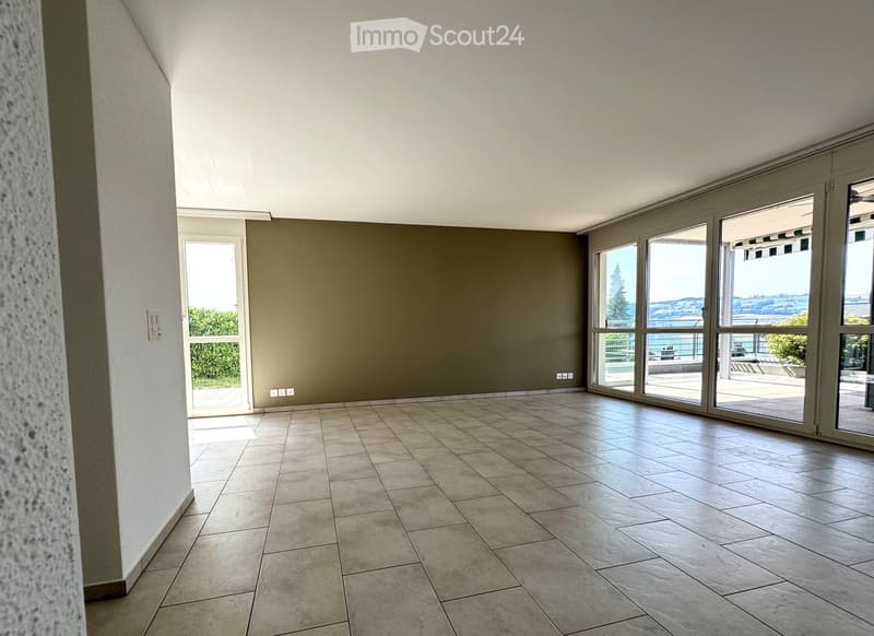 Empty room with tiled floor, large windows, and a door leading to an outdoor area.