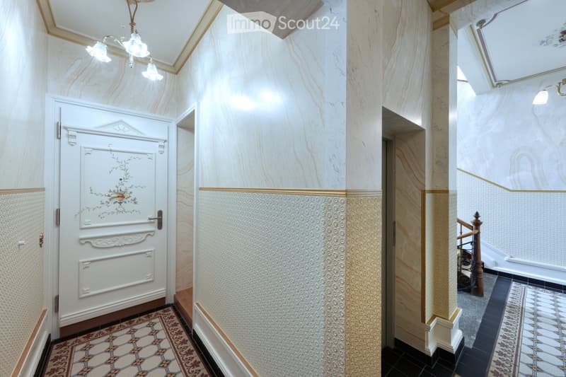 Elegant hallway with marble walls, decorative doors, ornate lighting fixture, and patterned tiles.