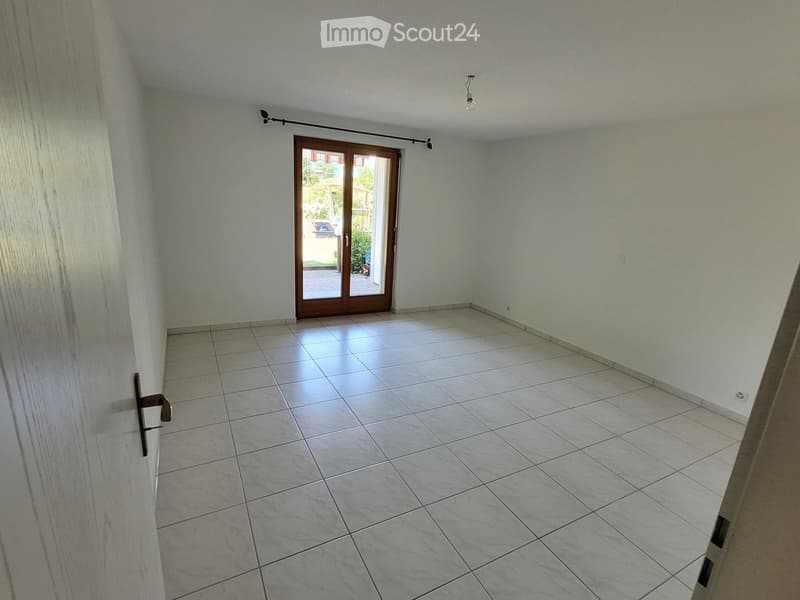 Empty room with tiled floor, light-colored walls, and a sliding glass door leading to an outdoor area.