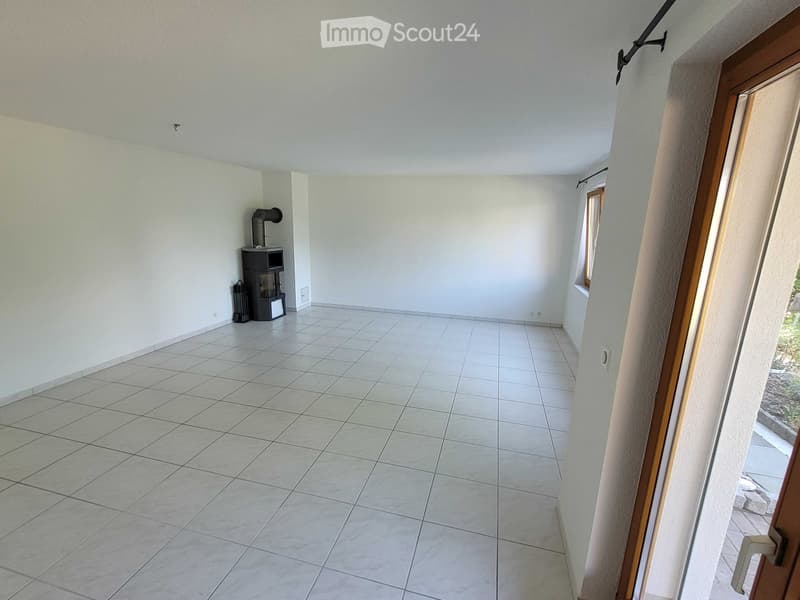 Empty room with tiled floor, white walls, and a small black wood-burning stove in the corner.