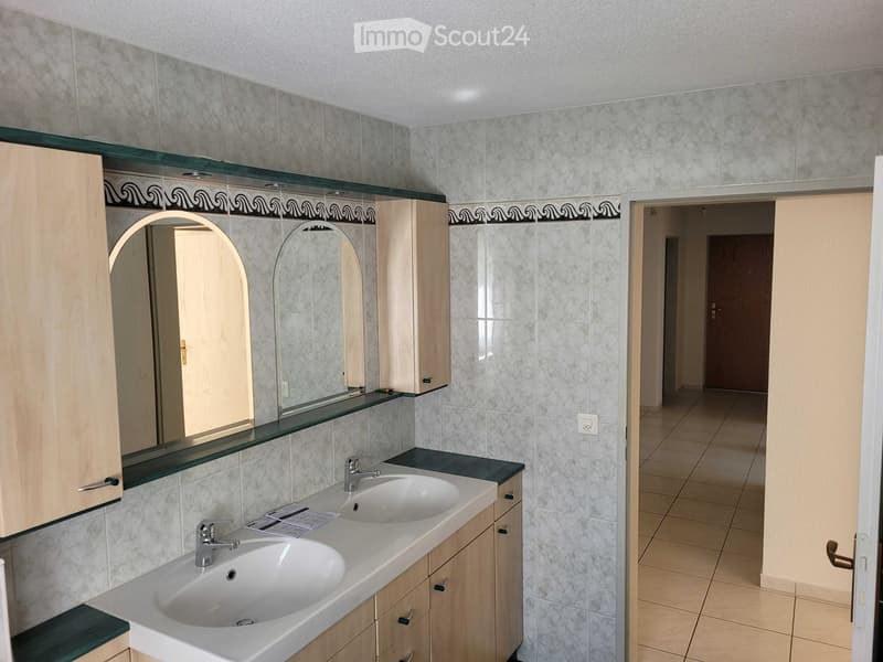 Bathroom with two sinks, wooden cabinets, and a large mirror above the vanity.