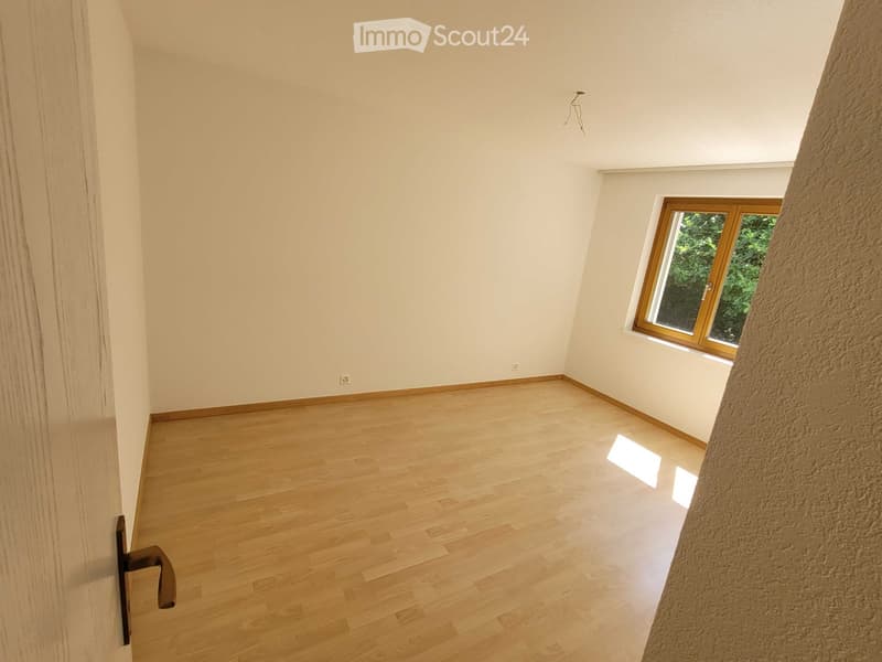 Empty room with light wooden flooring, white walls, and a single window with wooden frame. No furniture or equipment present.