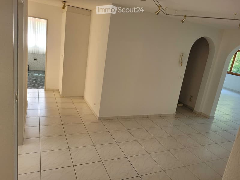 Empty hallway with tiled floor, white walls, and arched doorways leading to other rooms.
