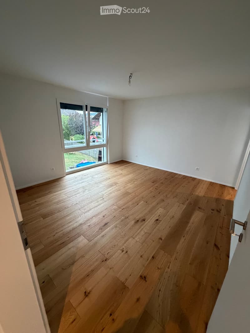 Empty room with wooden flooring, white walls, and a large window with blinds. No furniture or equipment is present.