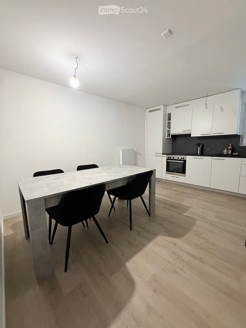 Modern kitchen and dining area with white cabinets, a marble dining table, and four black chairs.