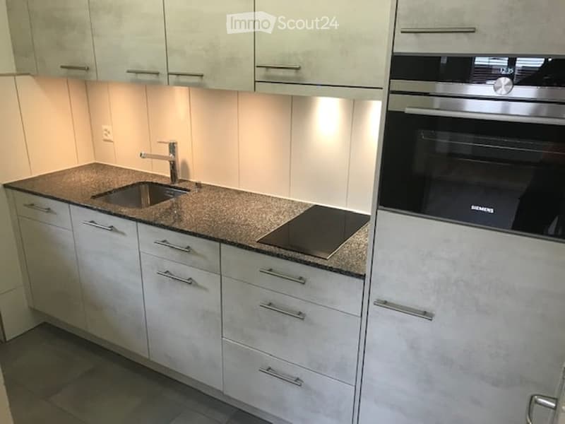 Modern kitchen with white cabinets, granite countertop, stainless steel sink, faucet, induction cooktop, and built-in oven.