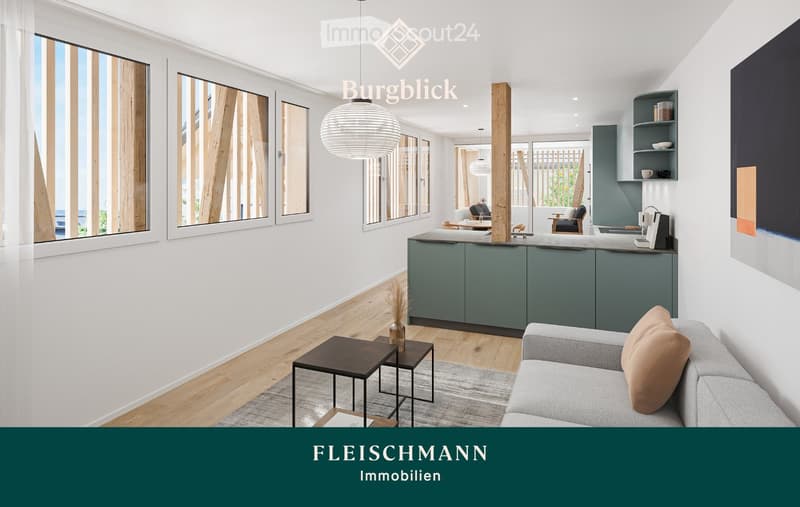 Modern open-plan living and dining area with a grey sofa, coffee table, kitchen island, and pendant lighting. The space features large windows, wooden flooring, and contemporary decor.