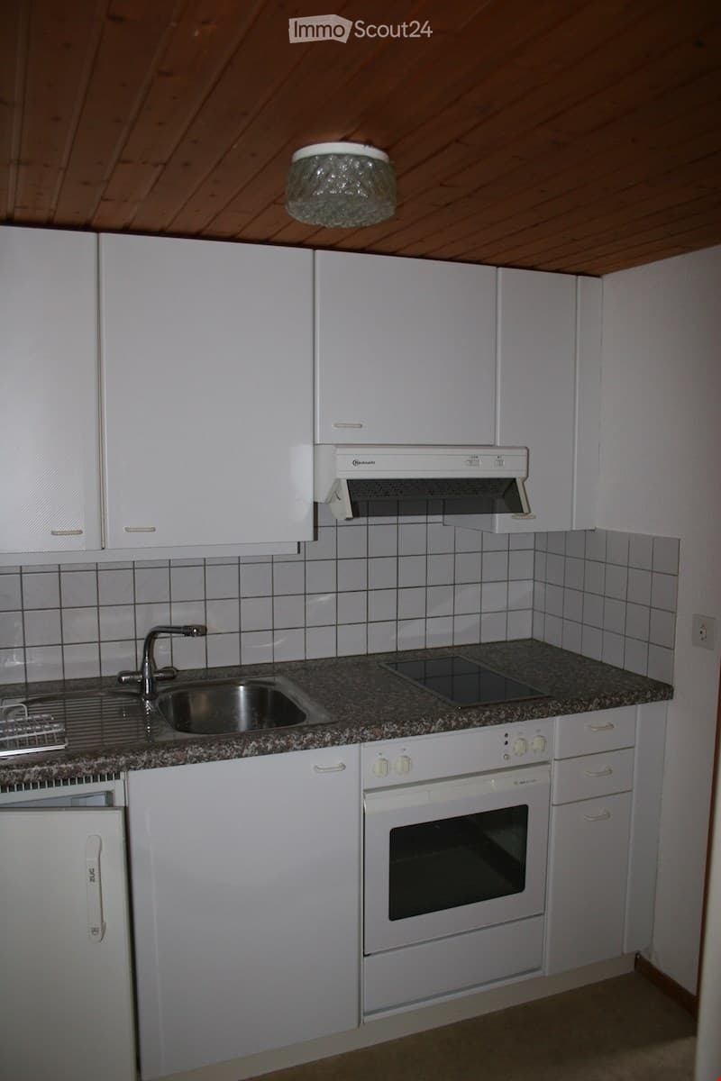Modern kitchen with white cabinets, granite countertop, stainless steel sink, and built-in oven.