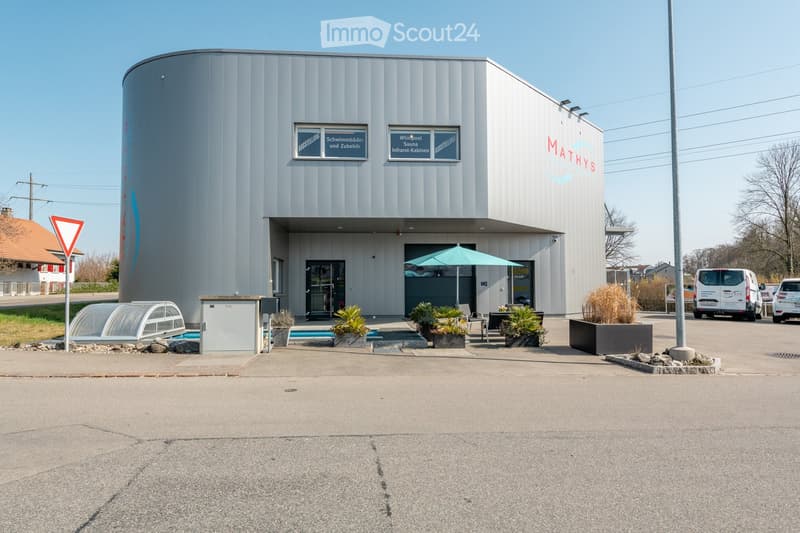 Modern building with a swimming pool area, outdoor seating, and signage for a wellness center.