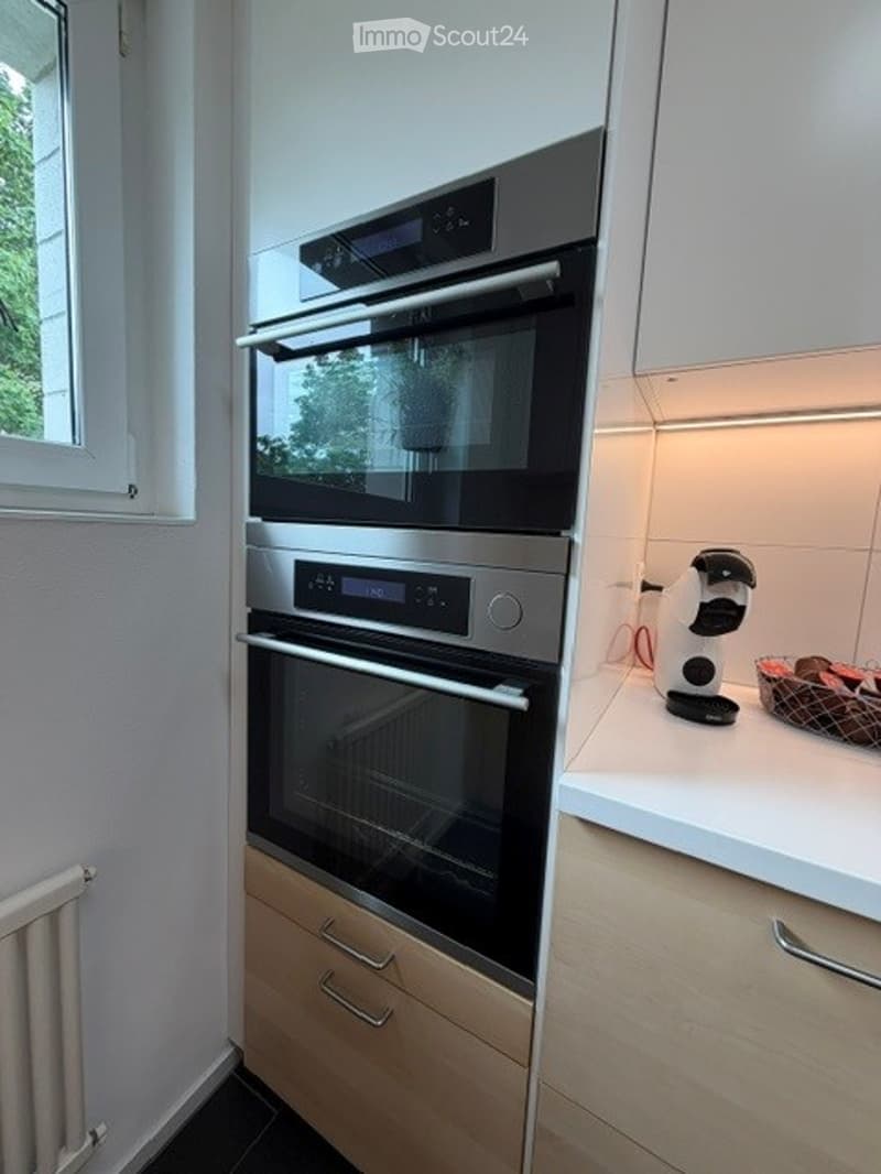 Modern kitchen with built-in ovens, a coffee maker, and a fruit basket on the counter.
