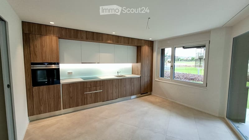 Modern kitchen with wooden and white cabinets, a sink, and an oven, featuring large windows and a clean, minimalist design.