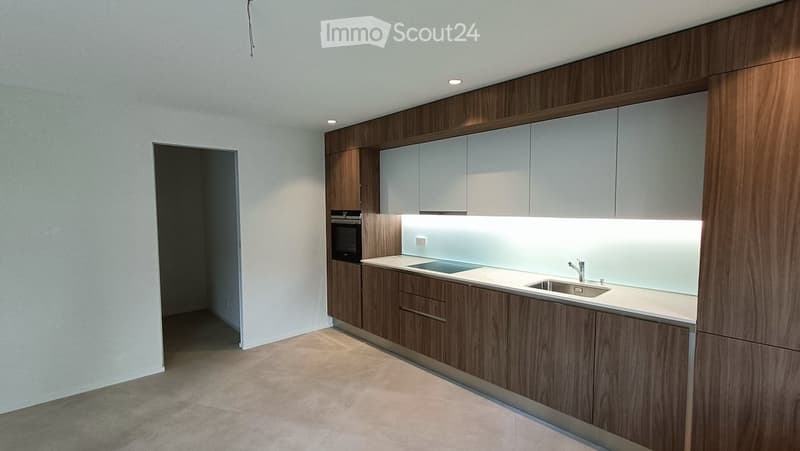 Modern kitchen with wooden cabinets, white countertops, and built-in appliances including a sink and oven.