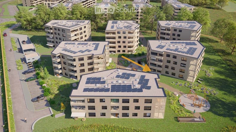 Aerial view of a residential complex with multiple apartment buildings, solar panels on rooftops, parking area, and green spaces including a playground.