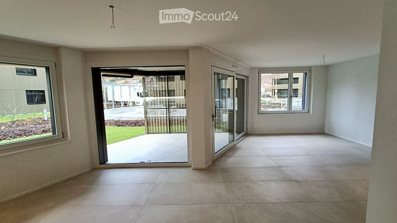 Empty room with tiled flooring, large windows, and sliding glass doors leading to an outdoor area.