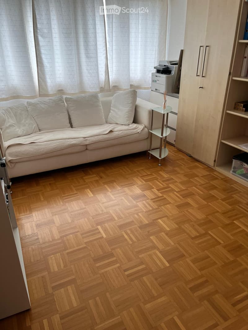 living room with couch, printer, bookshelves, wooden floor