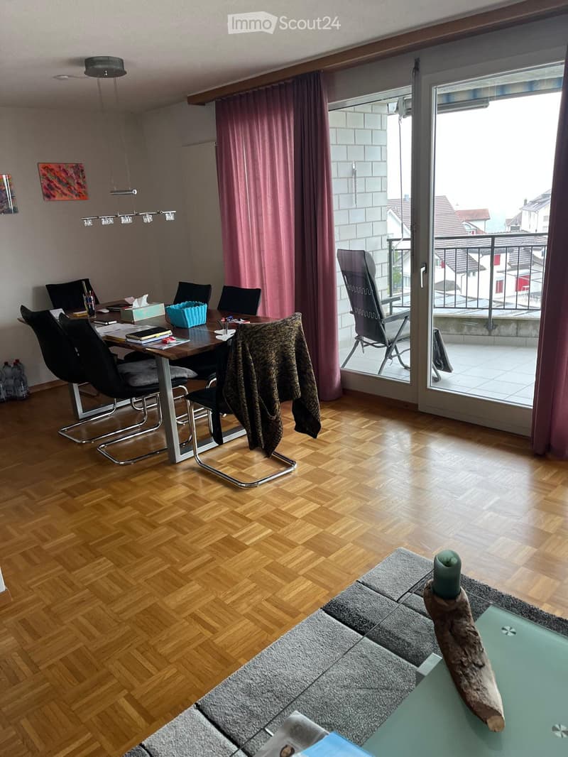 wooden dining table with 6 chairs, glass door leading to a balcony with a metal railing, white tile flooring