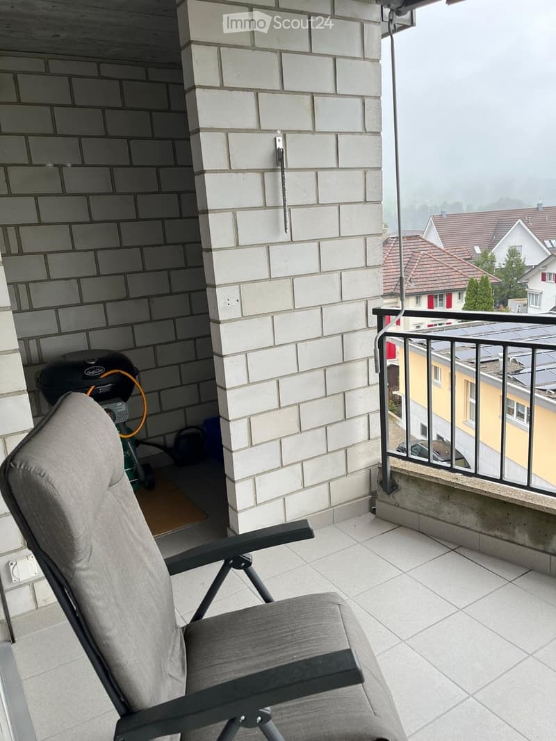 modern balcony with tile flooring, grey reclining chair, white brick wall, metal railing, storage shed