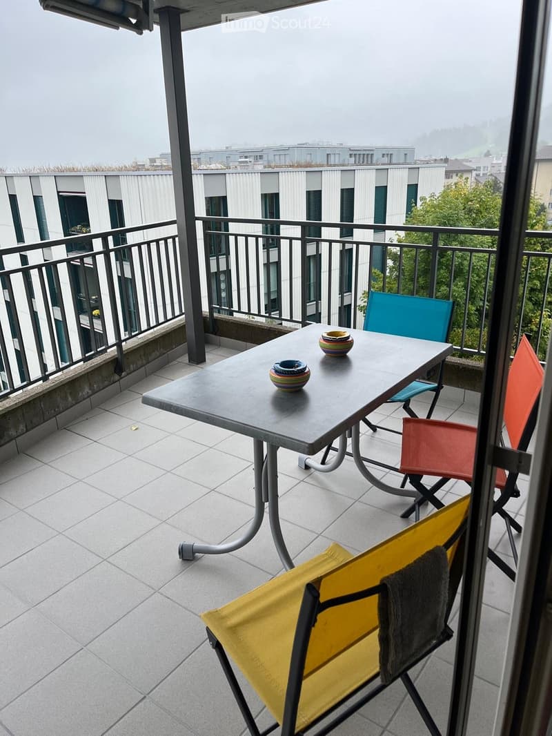 Balcony with table, chairs, two bowls, metal railing, tiled floor