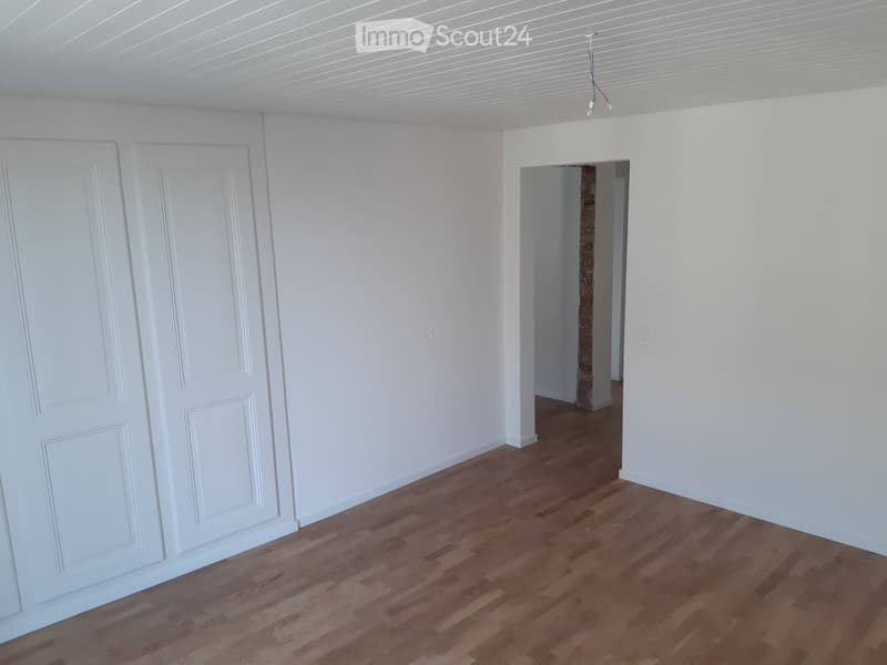 Empty room with white walls, wooden flooring, and two white doors. No furniture or equipment present.