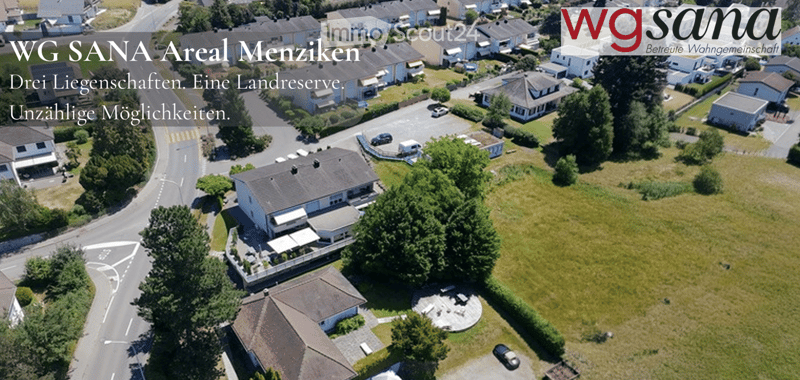 Aerial view of a residential area with multiple houses, roads, and greenery.