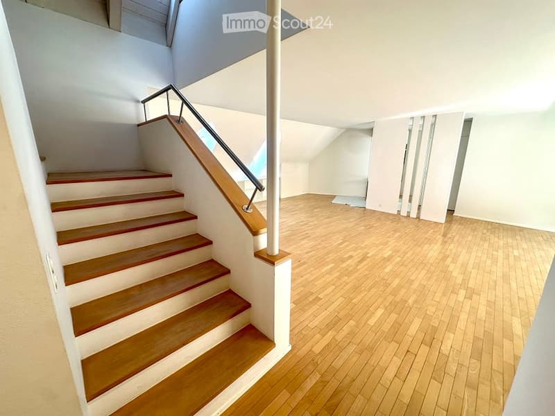 Stairs, hardwood floor, white walls, sloped ceiling, wooden handrail