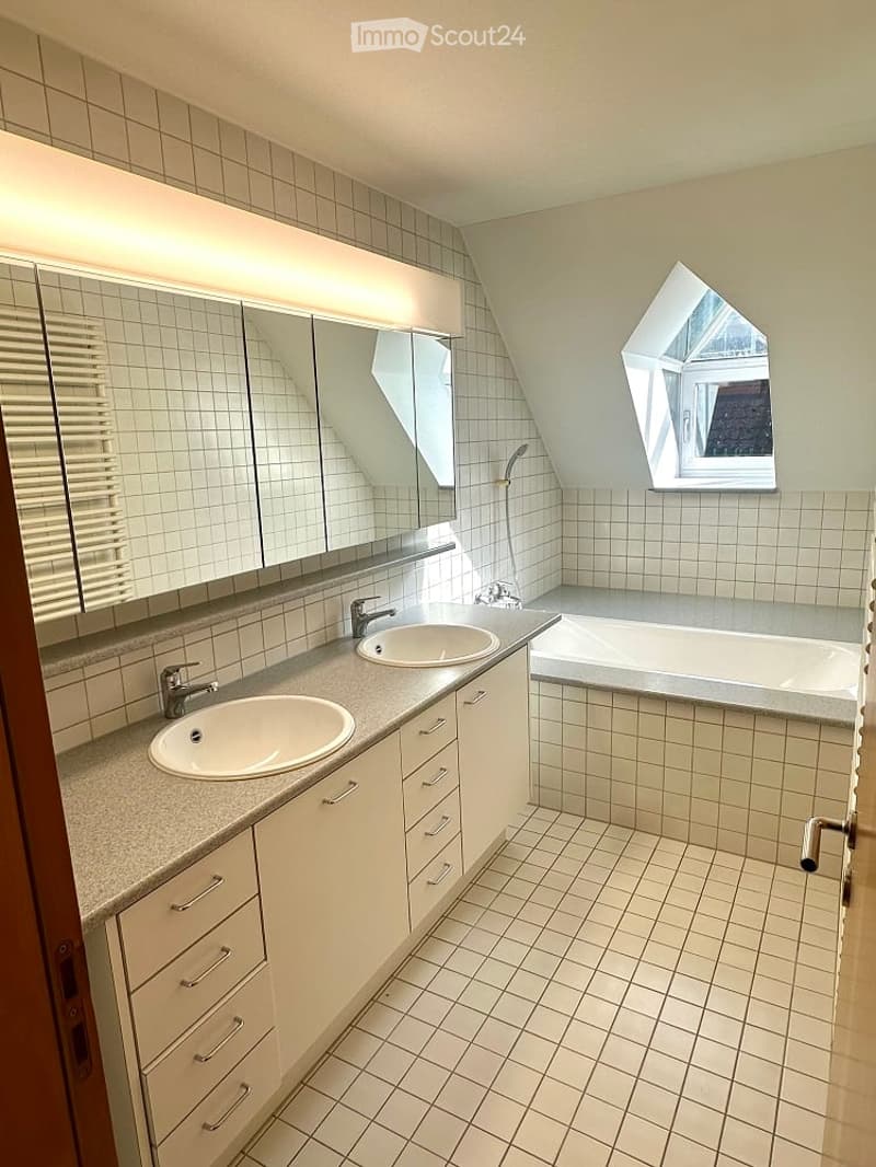 Bathroom with two sinks, large mirror, bathtub, and windows