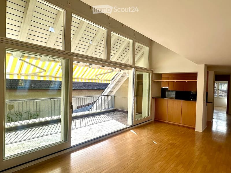 wooden floor, large sliding glass doors leading to a balcony, kitchen island, cabinets, modern appliances, slanted ceiling