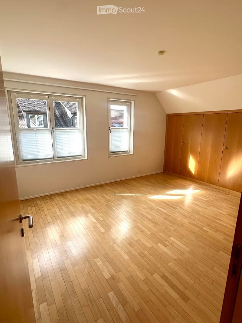 empty room with wooden floors, two windows, and built-in wardrobes