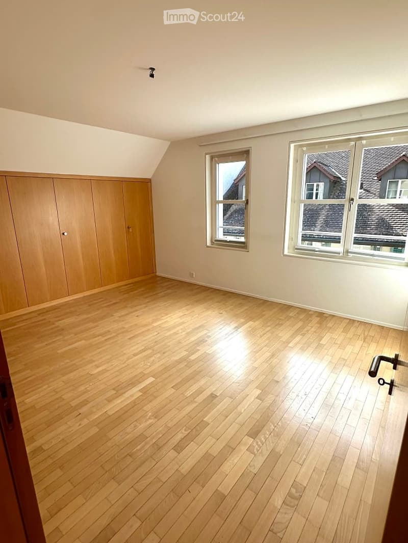 spacious room with wooden floor, built-in closets, two windows, clean and empty