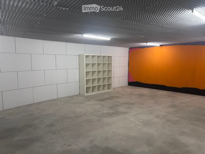Empty room with white tiled walls, a single white shelf, and a colorful abstract painting on one wall.