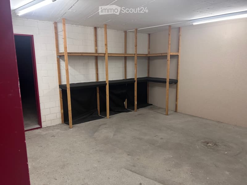 Empty room with exposed brick walls, wooden shelving units, and a concrete floor.