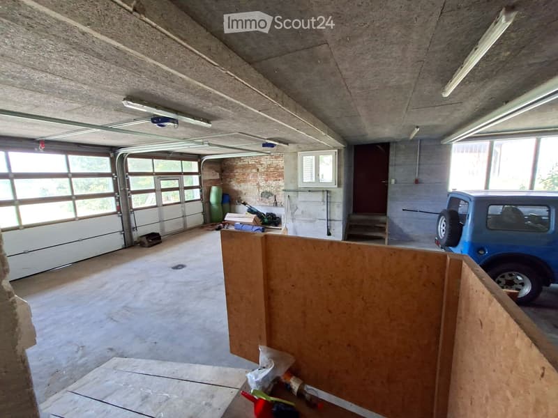 {"visible_features": ["Garage"], "type": "Garage", "objects": [], "description": "Empty garage with concrete floor, exposed ceiling beams, large garage door, and a blue vehicle parked inside.", "localized_descriptions": {"EN": "Empty garage with concrete
