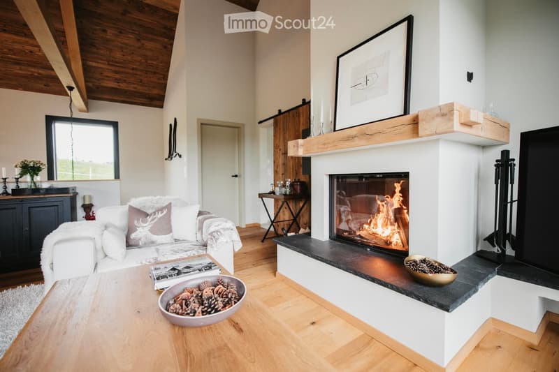 Modern living room with a white sofa, fireplace, wooden coffee table, and decorative bowls on the mantel.