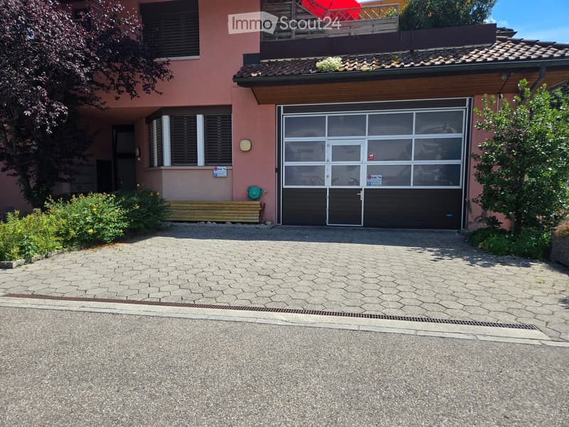 Two-story house with a large garage, pink exterior, and a balcony on the upper level.