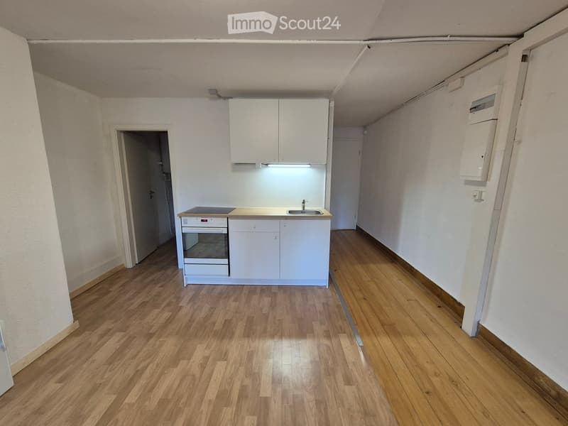 Modern kitchen with white cabinets, a built-in oven, and a sink, featuring wooden flooring and neutral-colored walls.