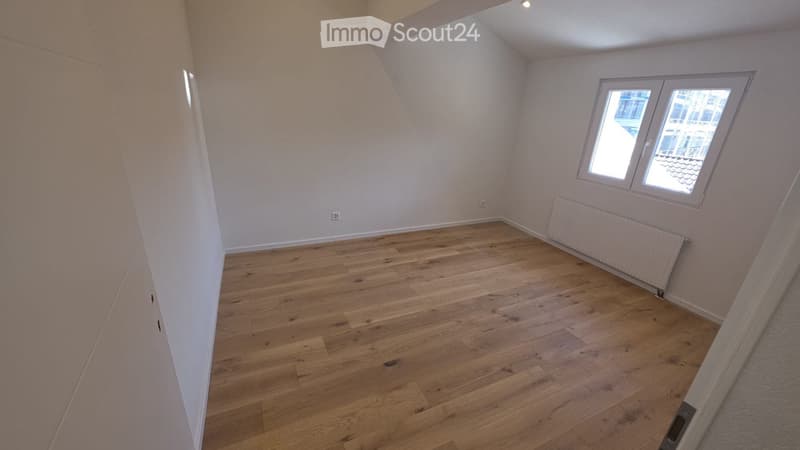 Empty room with wooden flooring, white walls, and a single window with white frame. No furniture or equipment present.