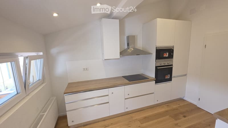 Modern kitchen with white cabinets, wooden countertops, and stainless steel appliances including an oven and range hood.