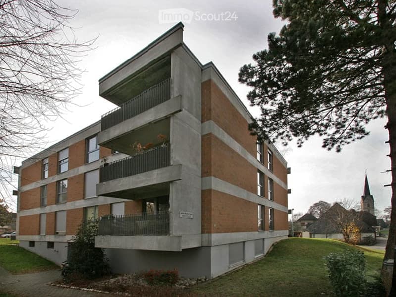 3 story apartment building, brick and concrete, multiple balconies, green grass, trees