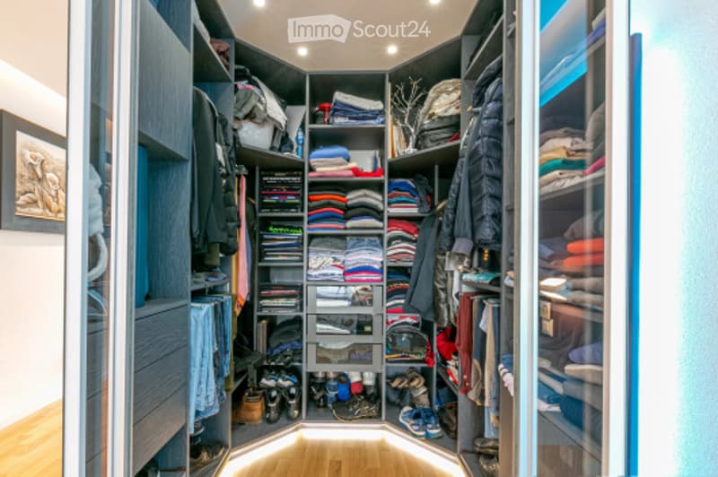 A spacious, well-organized walk-in closet with built-in wardrobes and shelves, filled with neatly arranged clothing, shoes, and accessories.