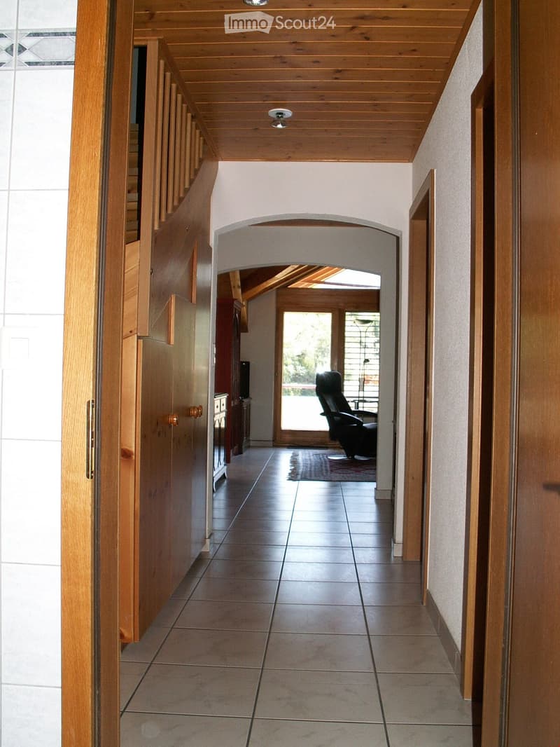 wooden interior, tiled floor, arched hallway, wooden door, large windows, glass door, lounge chair, cabinet