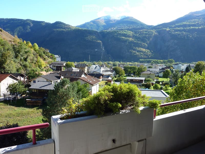 Mountain town view, houses, lush greenery, mountains in background