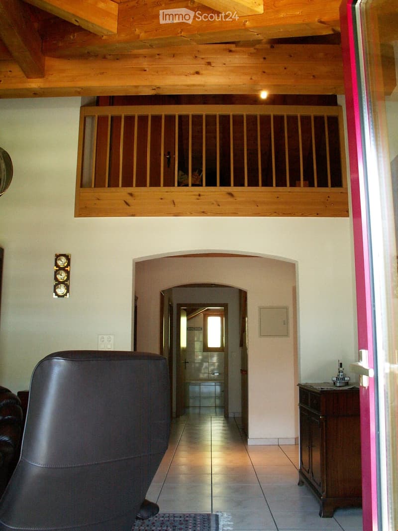 living room, wooden beams, balcony, light wood flooring, leather armchair, wooden cabinet