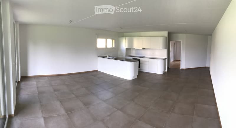 Empty kitchen with white cabinets, a countertop, and tiled flooring. No furniture or appliances are present.