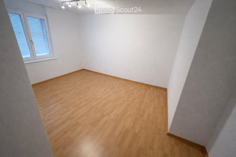 Empty room with wooden flooring, white walls, and a window with blinds. No furniture or equipment is present.