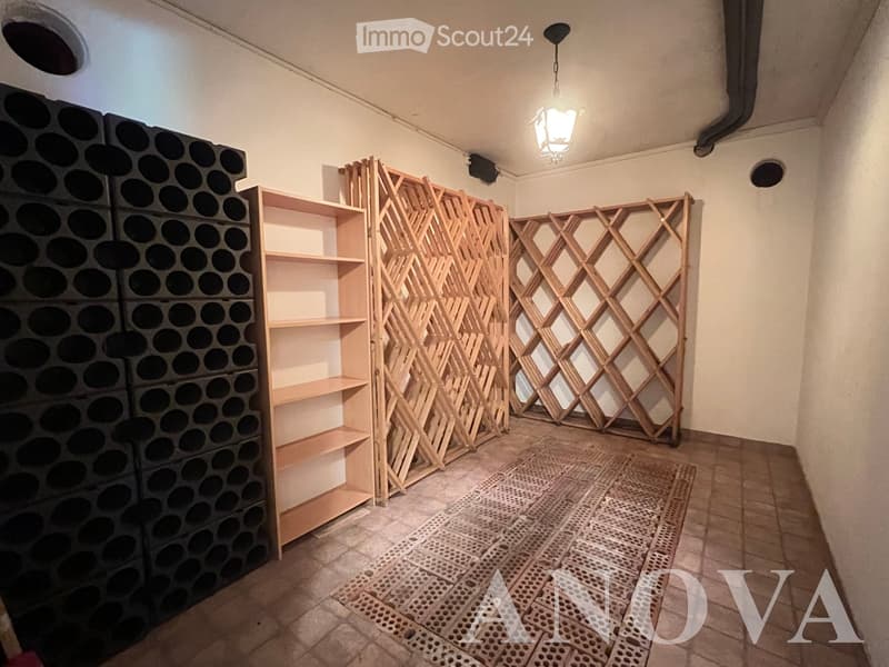 Empty room with wooden shelving units, decorative wooden screens, and a hanging light fixture. The floor is tiled, and the walls are plain.