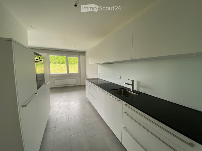 Modern kitchen with white cabinets, black countertop, stainless steel sink, and tiled floor.