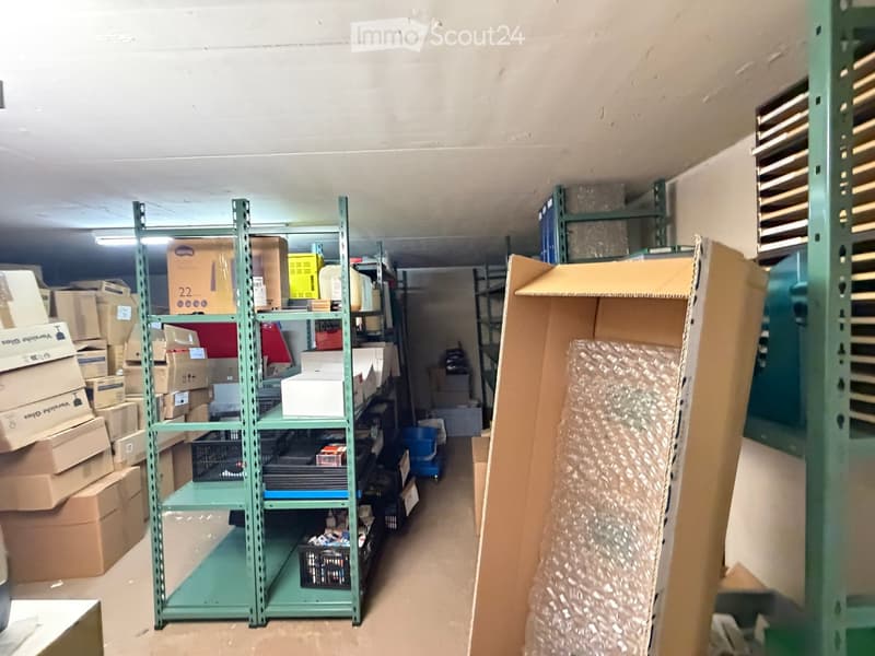 An empty storage room with metal shelving units and cardboard boxes stacked on the floor and shelves.